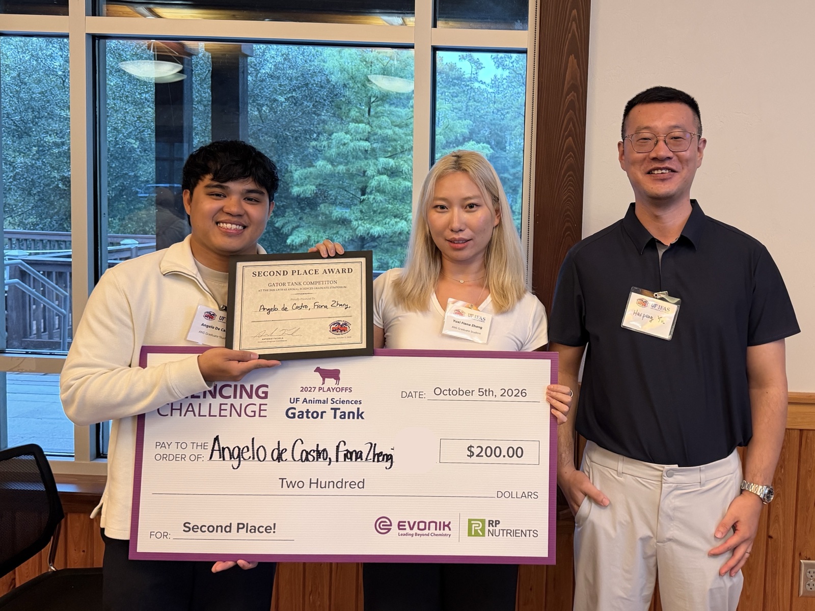 Angelo De Castro and Yuxi Zhang holding the Gator Tank second place check, with Dr. Haipeng Yu